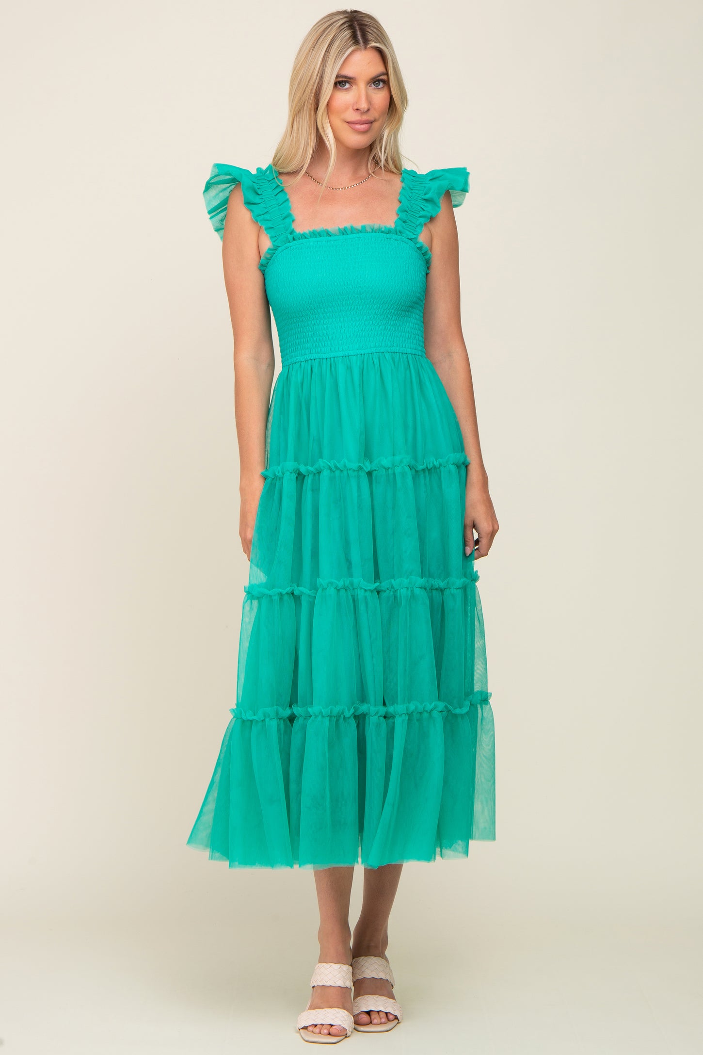 woman wearing a teal tiered maxi dress with ruffled sleeves and a fitted bodice