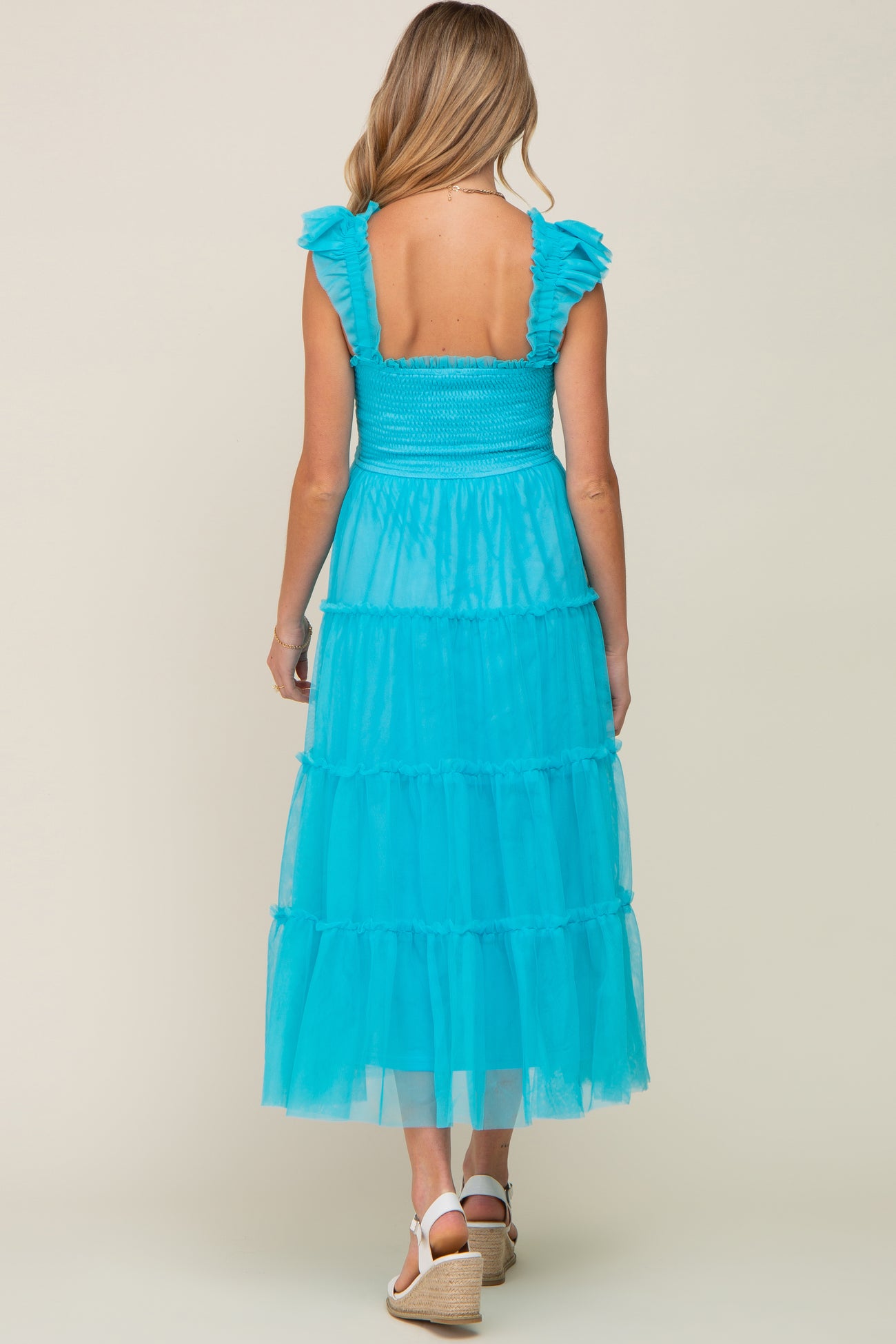 woman wearing a teal tiered maxi maternity dress with ruffle straps and a smocked bodice, showcasing a baby bump