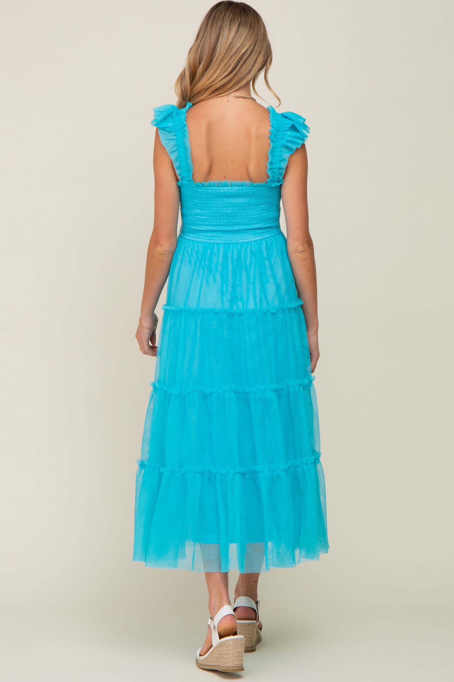 woman wearing a teal tiered maxi maternity dress with ruffle straps and a smocked bodice, showcasing a baby bump