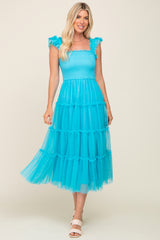 woman wearing a bright turquoise tiered tulle dress with ruffle straps and a smocked bodice