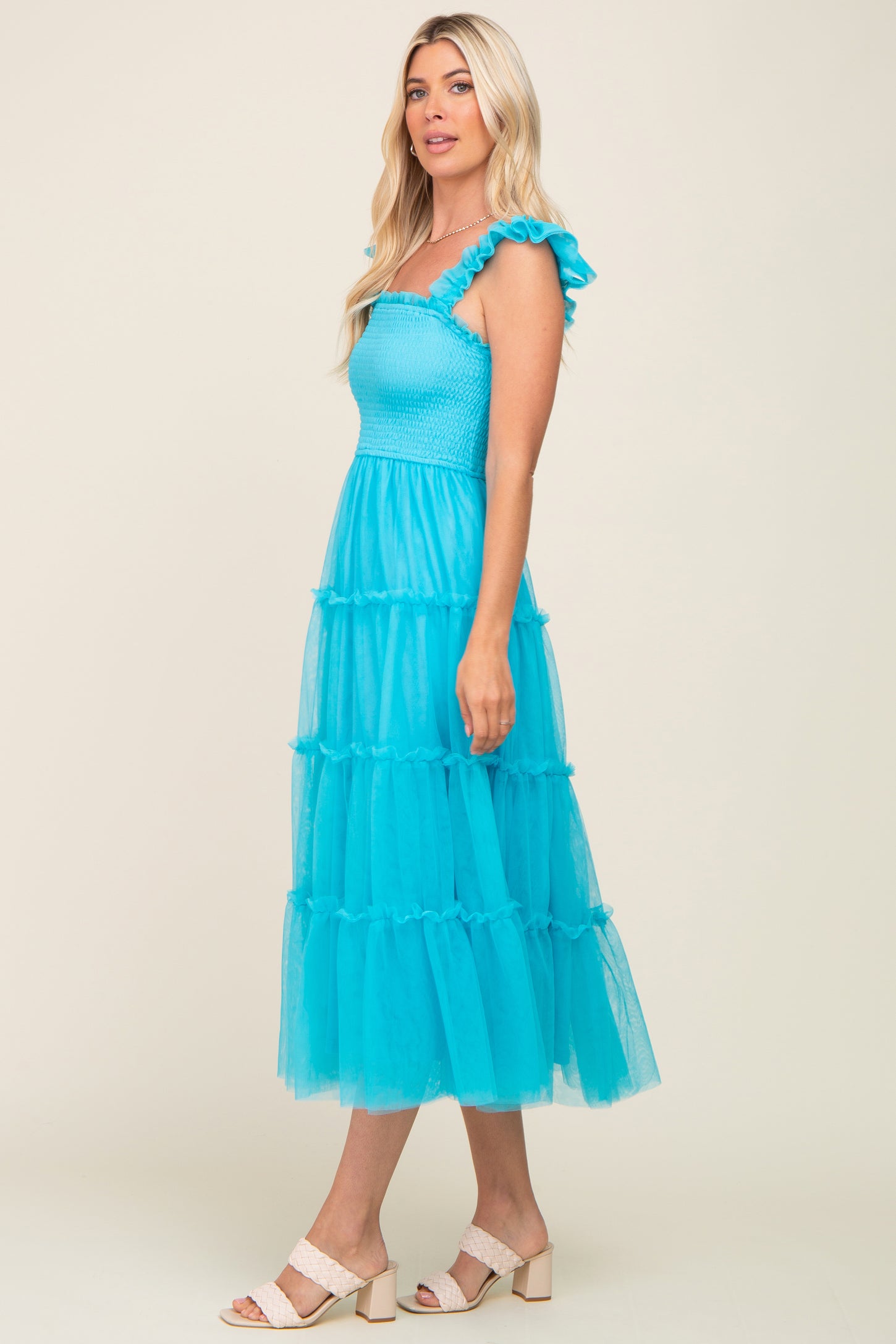 woman wearing a bright turquoise tiered midi dress with ruffle straps and a smocked bodice