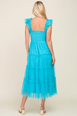 woman wearing a back view of a tiered aqua blue maxi dress with ruffled sleeves and a smocked bodice