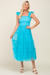 woman wearing a bright turquoise tiered tulle midi dress with ruffle sleeves and a smocked bodice
