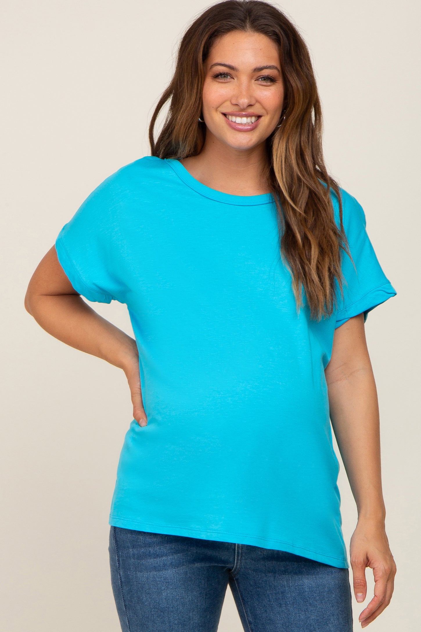 woman wearing a teal short sleeve maternity top and showing her baby bump