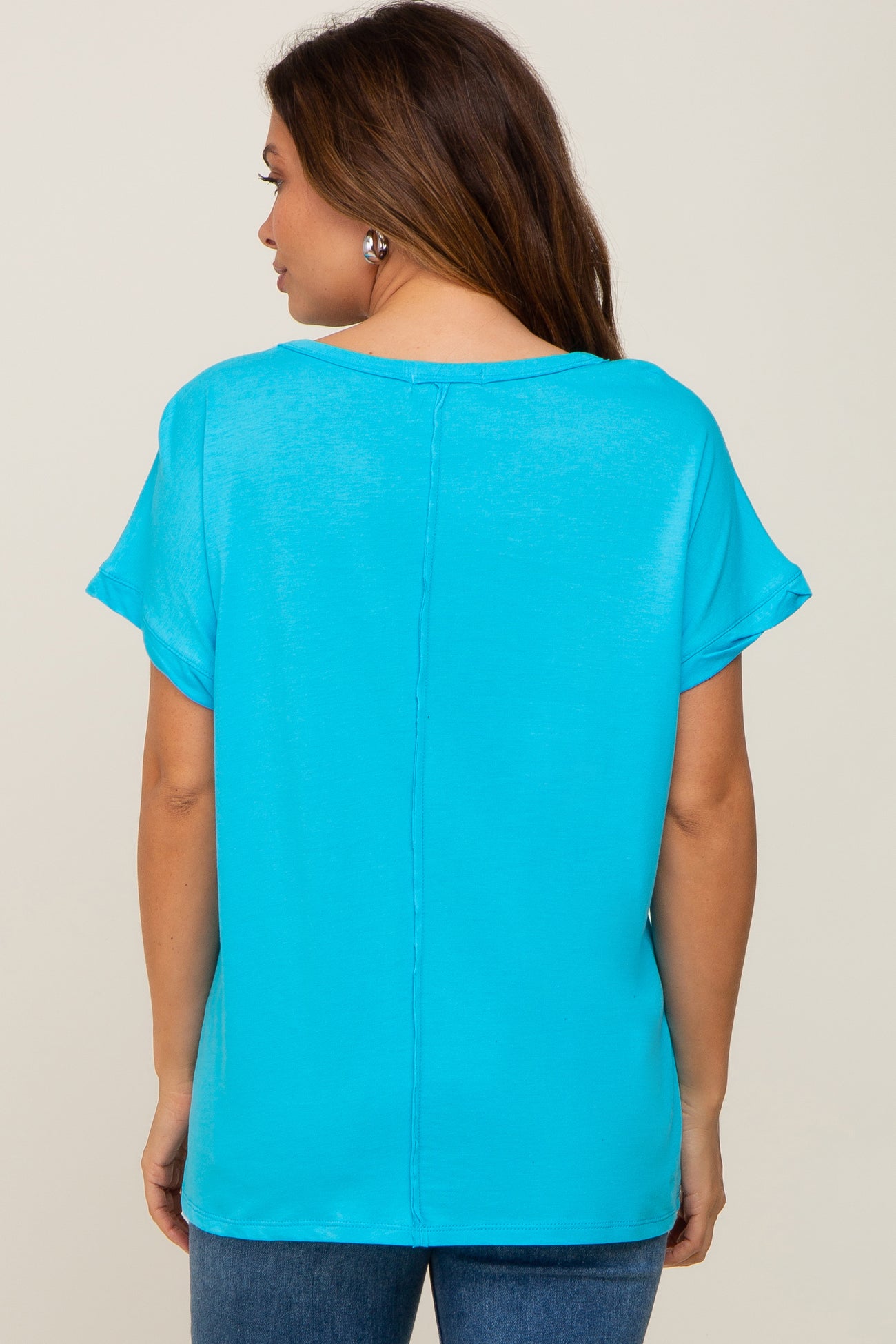 woman wearing a bright turquoise maternity top with short sleeves and a relaxed fit, seen from the back