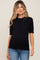 woman wearing a black short sleeve maternity sweater and blue jeans with a visible baby bump