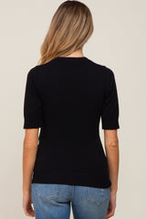 woman wearing a black short sleeve maternity top, view from the back, paired with light blue jeans
