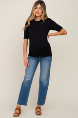 woman wearing a black short sleeve maternity top and distressed blue jeans, showing her baby bump