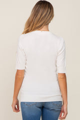 Back view of a woman wearing a white short sleeve knit sweater and blue jeans
