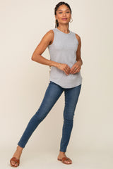 Woman wearing a grey ribbed sleeveless tank top and blue skinny jeans with brown leather sandals