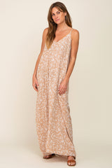 woman wearing a tan leaf patterned maxi dress with a v-neckline and spaghetti straps