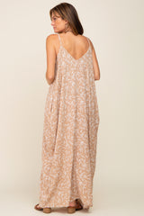woman wearing a beige maxi dress with a leaf print and a v-back detail, shown from the back
