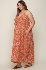 woman wearing an orange floral maternity maxi dress with pockets and holding her baby bump