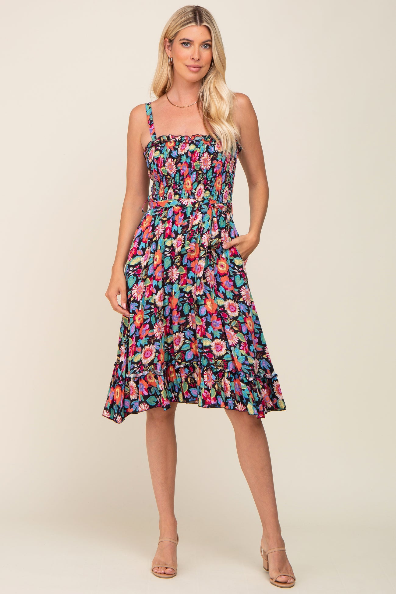 woman wearing a floral print sundress with a smocked bodice and pockets, styled with strappy heels