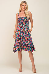 woman wearing a floral print sundress with a smocked bodice and pockets, styled with strappy heels
