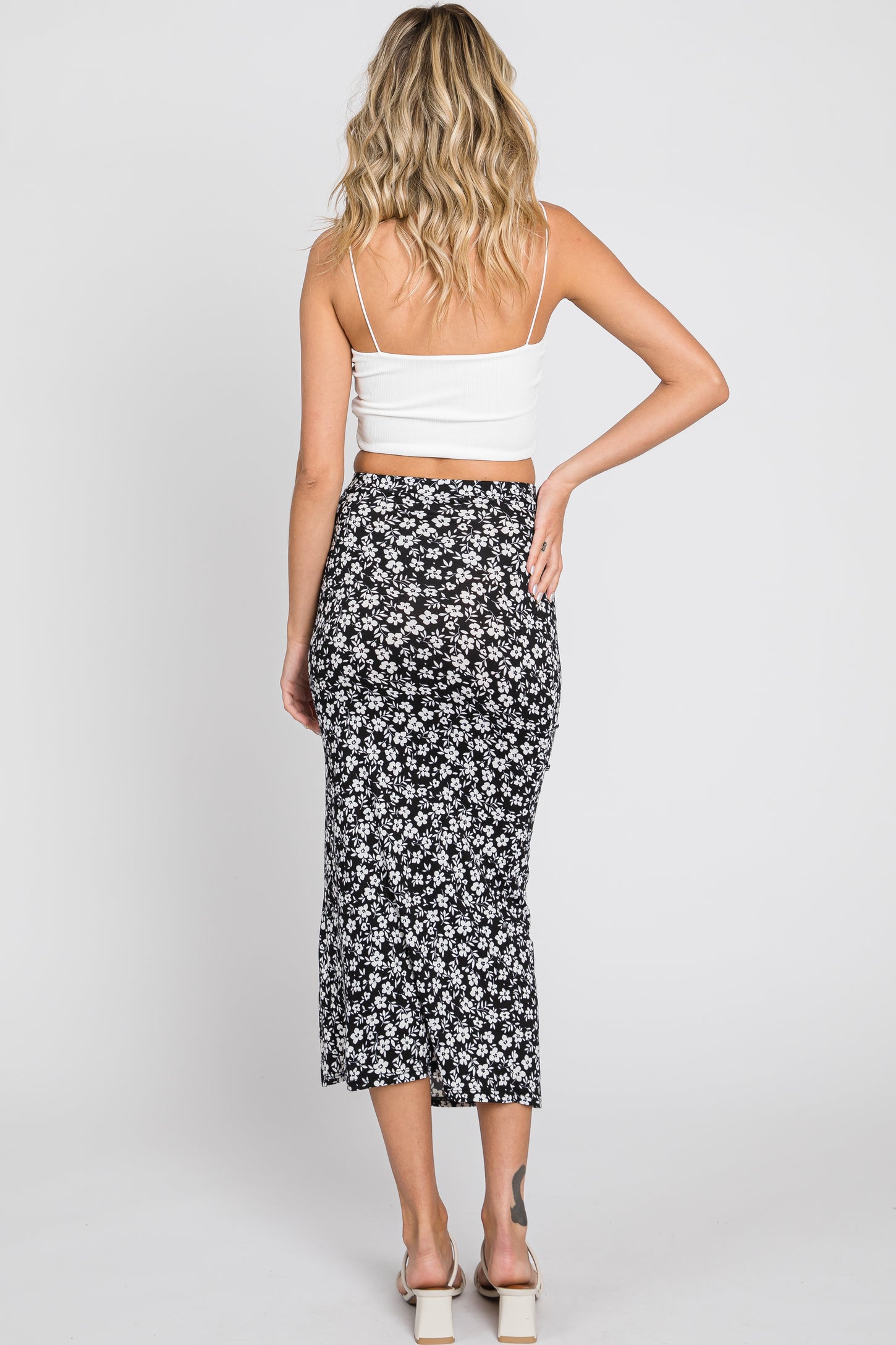 woman from behind wearing a white crop top and a black and white floral midi skirt