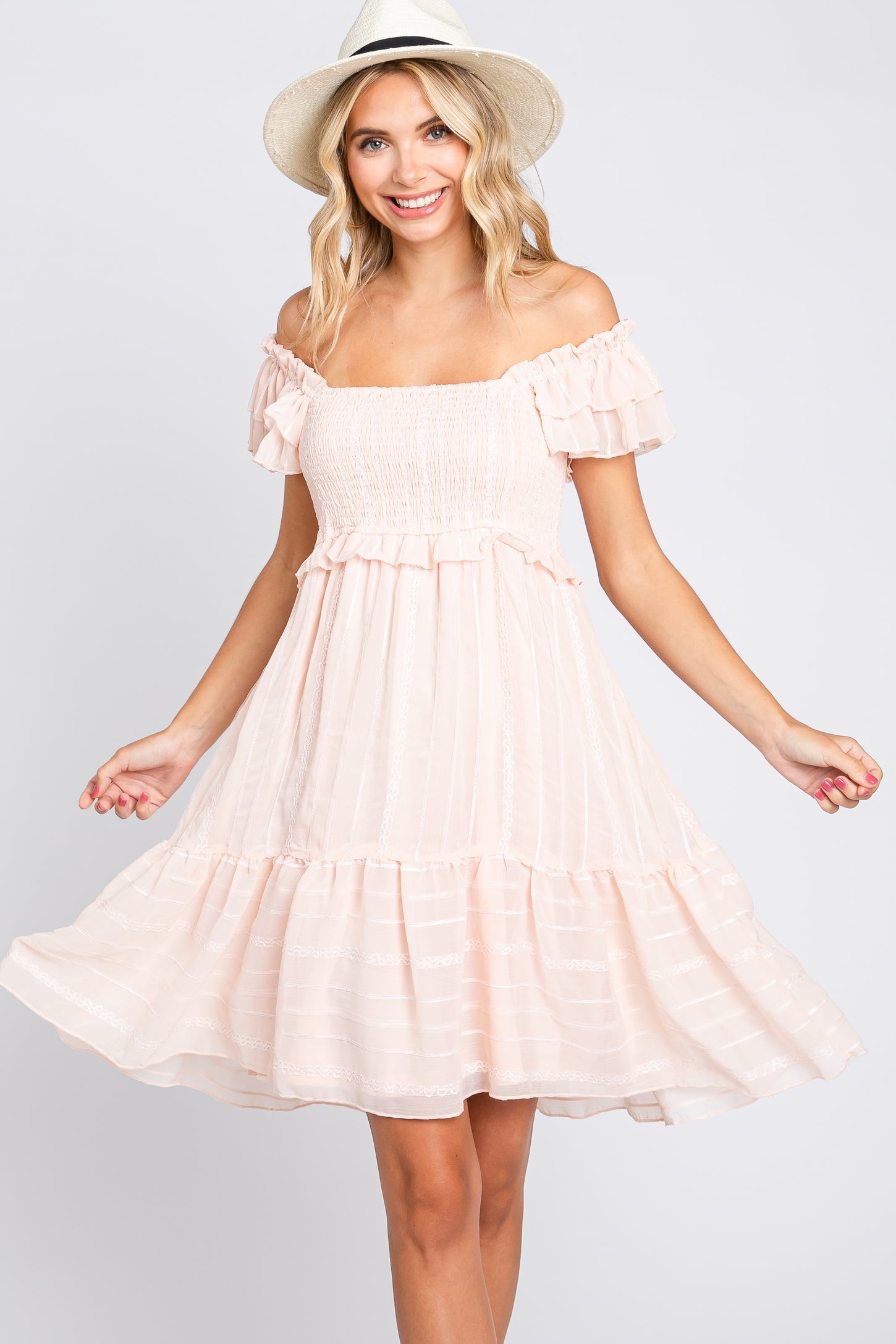 woman in a light pink off-the-shoulder smocked mini dress and straw hat