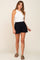 woman wearing white ribbed tank top and black high-waisted shorts with olive green sandals