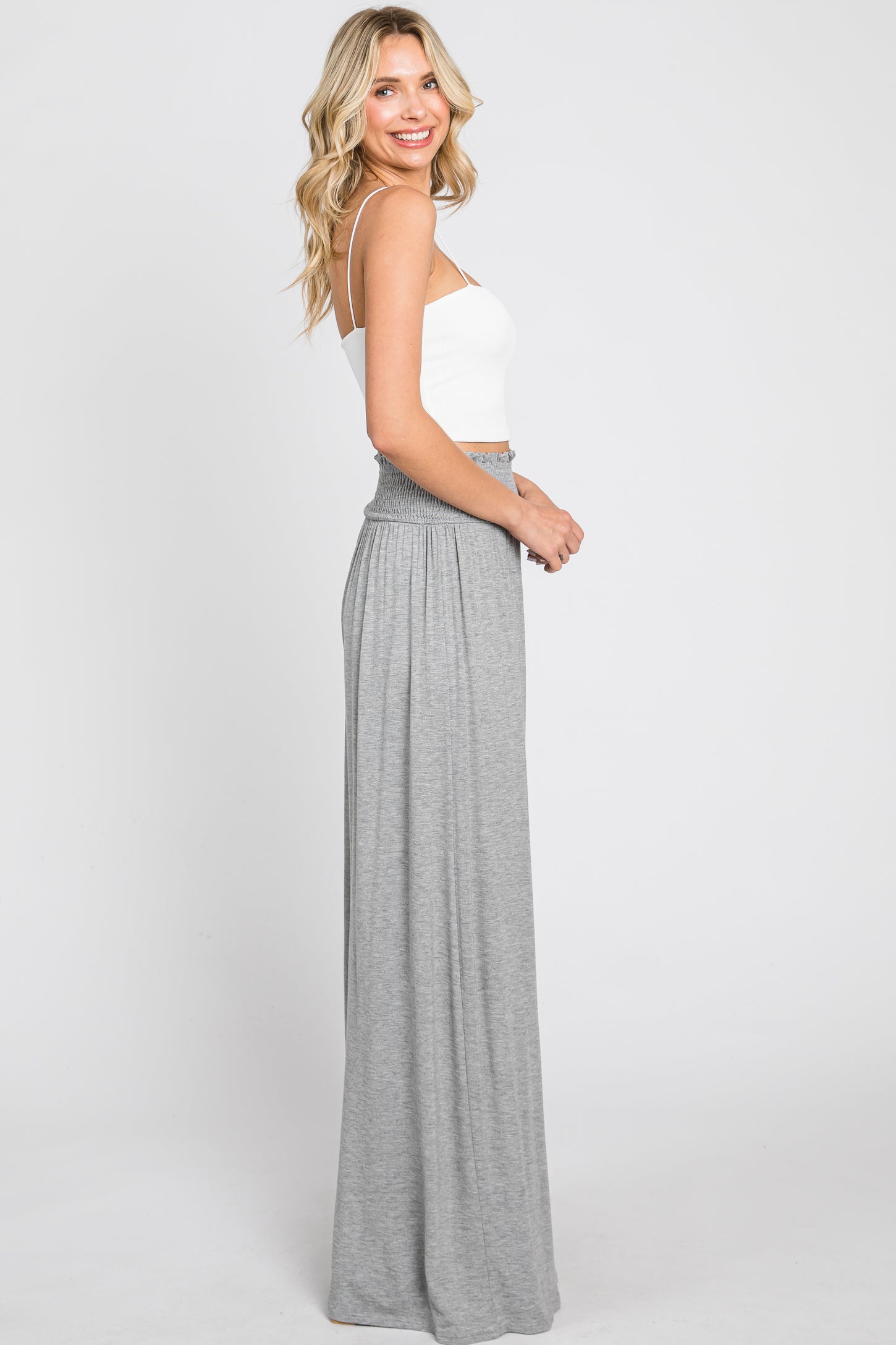 woman wearing a white spaghetti strap crop top and a long grey maxi skirt with a smocked waistband