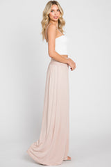 woman wearing a white spaghetti strap crop top and a long light pink maxi skirt against a white background
