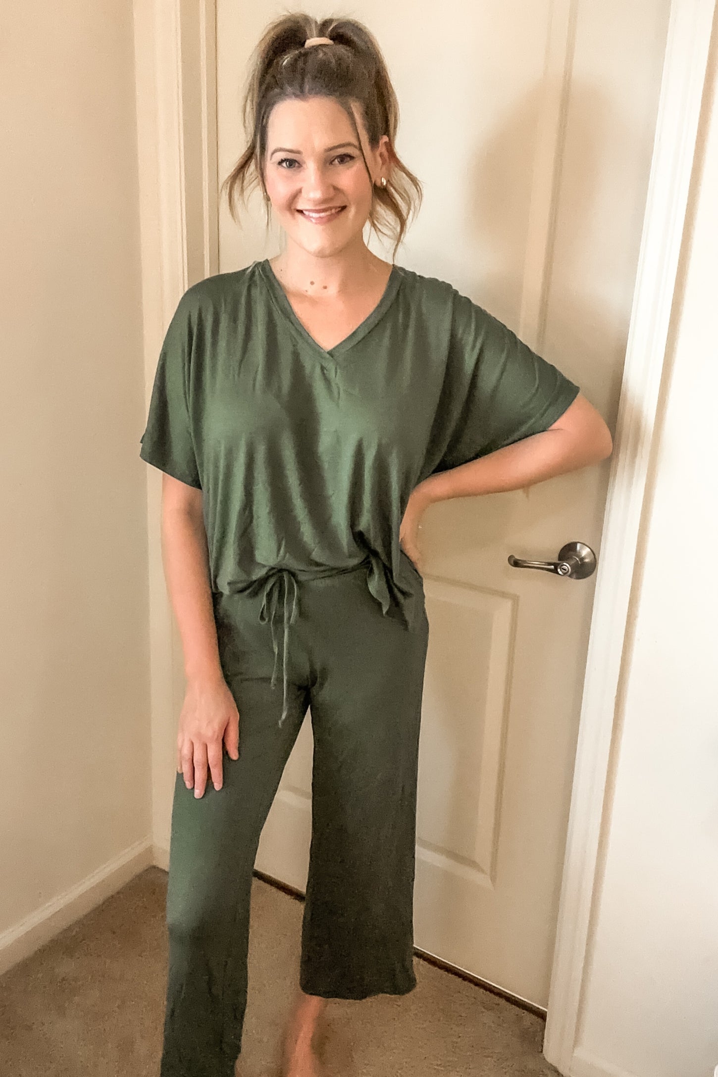 woman wearing a relaxed fit olive green two-piece lounge set with a v-neck and drawstring shorts