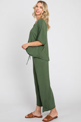 woman wearing a green two-piece loungewear set with a loose top and wide-leg pants