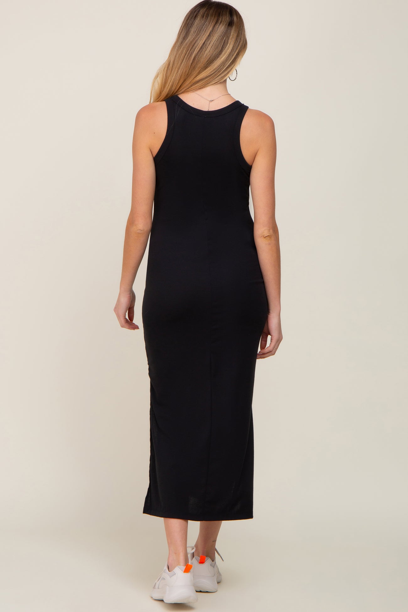 back view of a woman wearing a black sleeveless ribbed maxi dress and white sneakers
