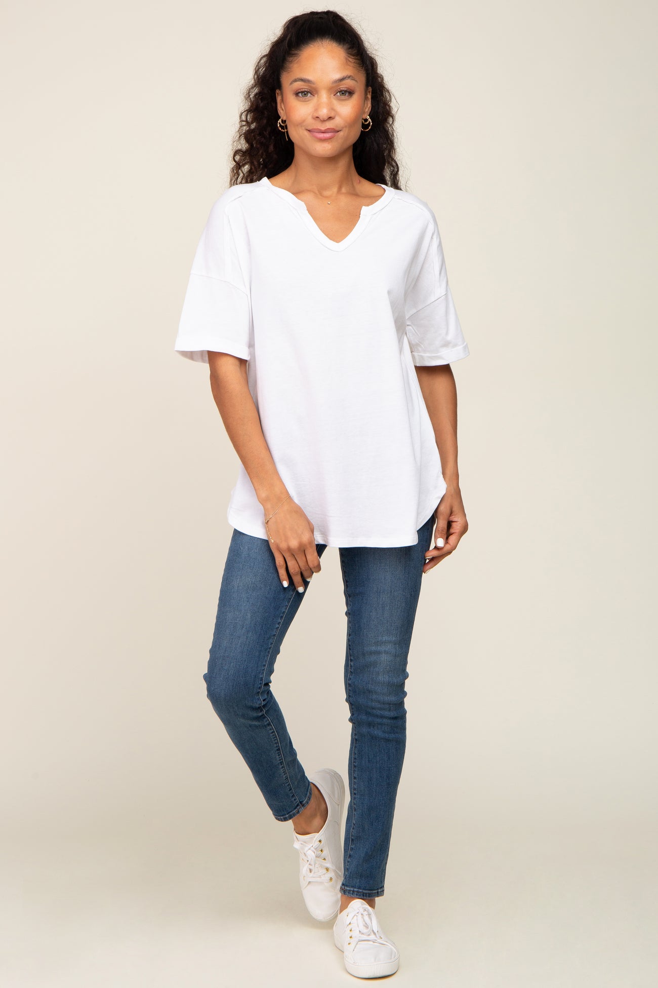 woman wearing a loose white v-neck t-shirt and blue skinny jeans with white sneakers