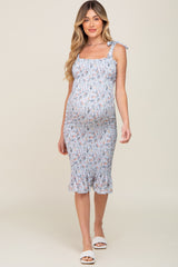 woman wearing a light blue floral maternity dress with ruffled straps and a fitted silhouette, showing her baby bump