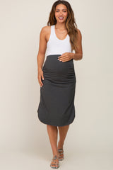 woman wearing a white tank top and a dark gray maternity skirt that highlights her baby bump