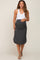 woman wearing a white tank top and a dark gray maternity skirt that highlights her baby bump