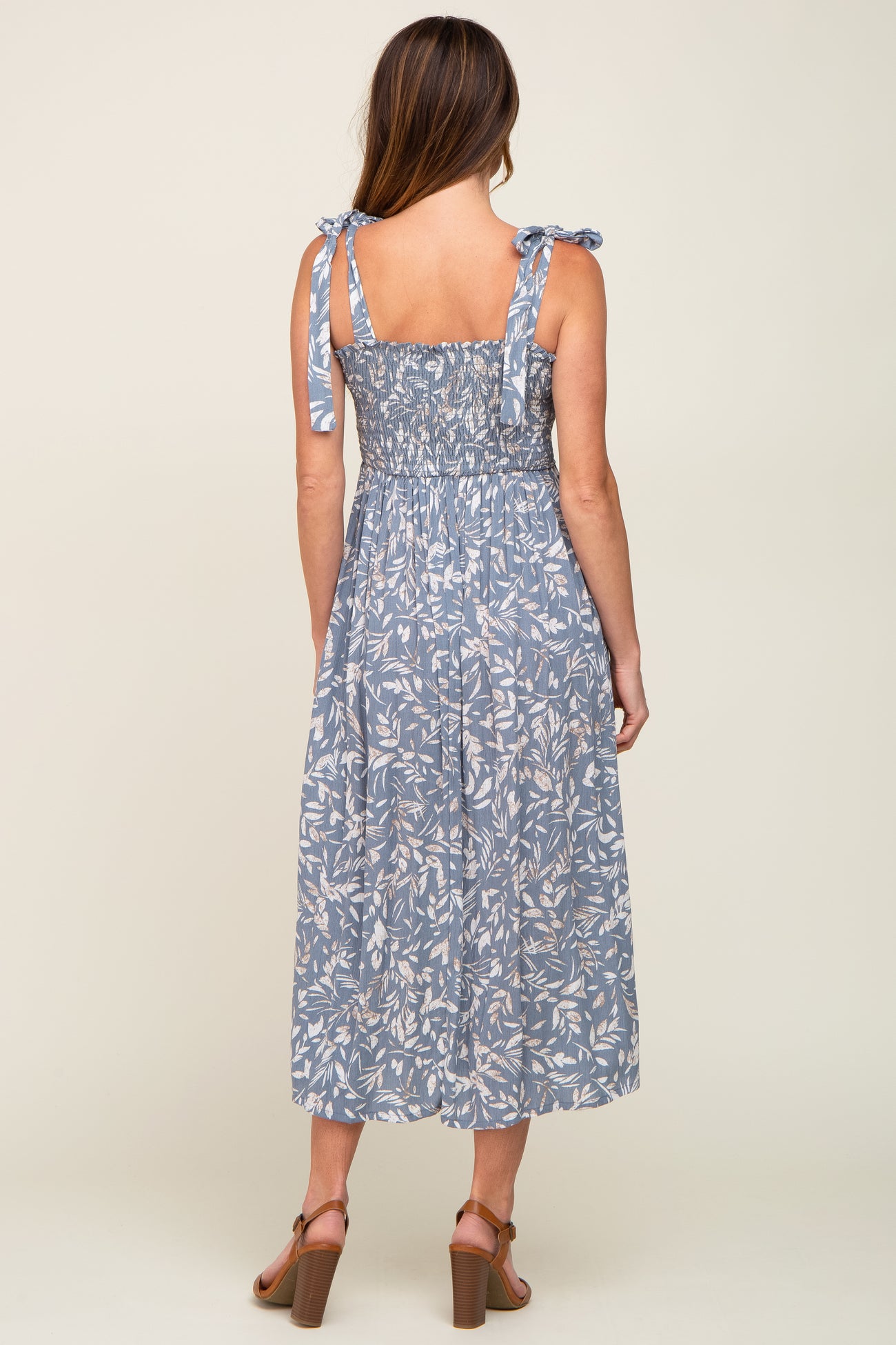 woman wearing a blue floral midi dress with tie straps and smocked back, view from the back
