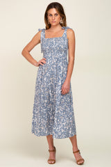 woman wearing a blue floral smocked midi dress with tie straps and brown sandals