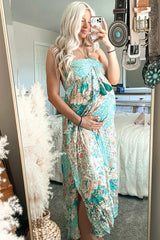 pregnant woman with blonde hair wearing a floral turquoise maternity maxi dress taking a mirror selfie