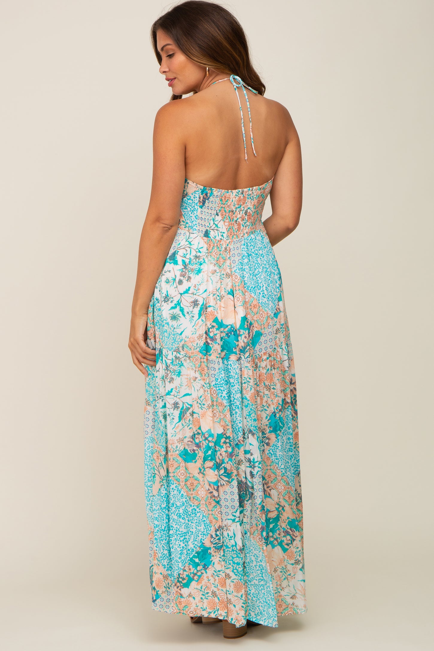 woman wearing a blue floral patchwork halter neck maxi dress with an open back