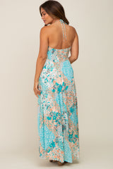 woman wearing a blue floral patchwork halter neck maxi dress with an open back