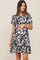 woman wearing a black floral maternity dress with short sleeves and ruffle hem, showing her baby bump
