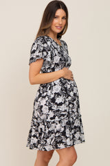 woman wearing a black floral maternity dress with ruffle hem and baby bump visible