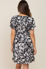 woman wearing a black floral maternity dress with short sleeves and a ruffled hem, showing her baby bump from the back