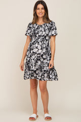 woman wearing a black floral maternity dress with short sleeves and a ruffled hem, showcasing her baby bump