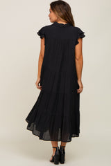 Woman from behind wearing a black tiered midi dress with ruffle sleeves and black high heel sandals