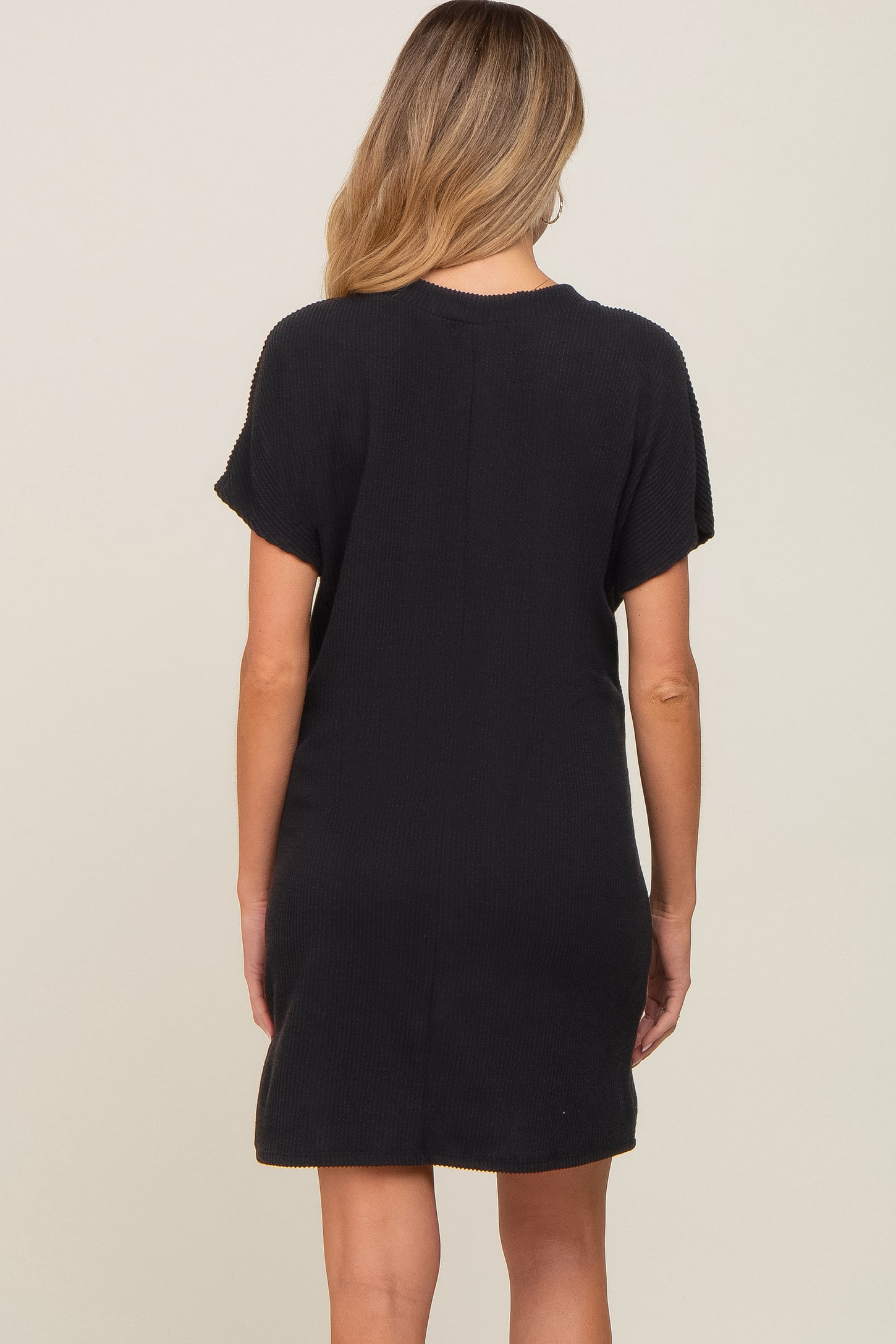 woman wearing a black maternity t-shirt dress with short sleeves, viewed from the back