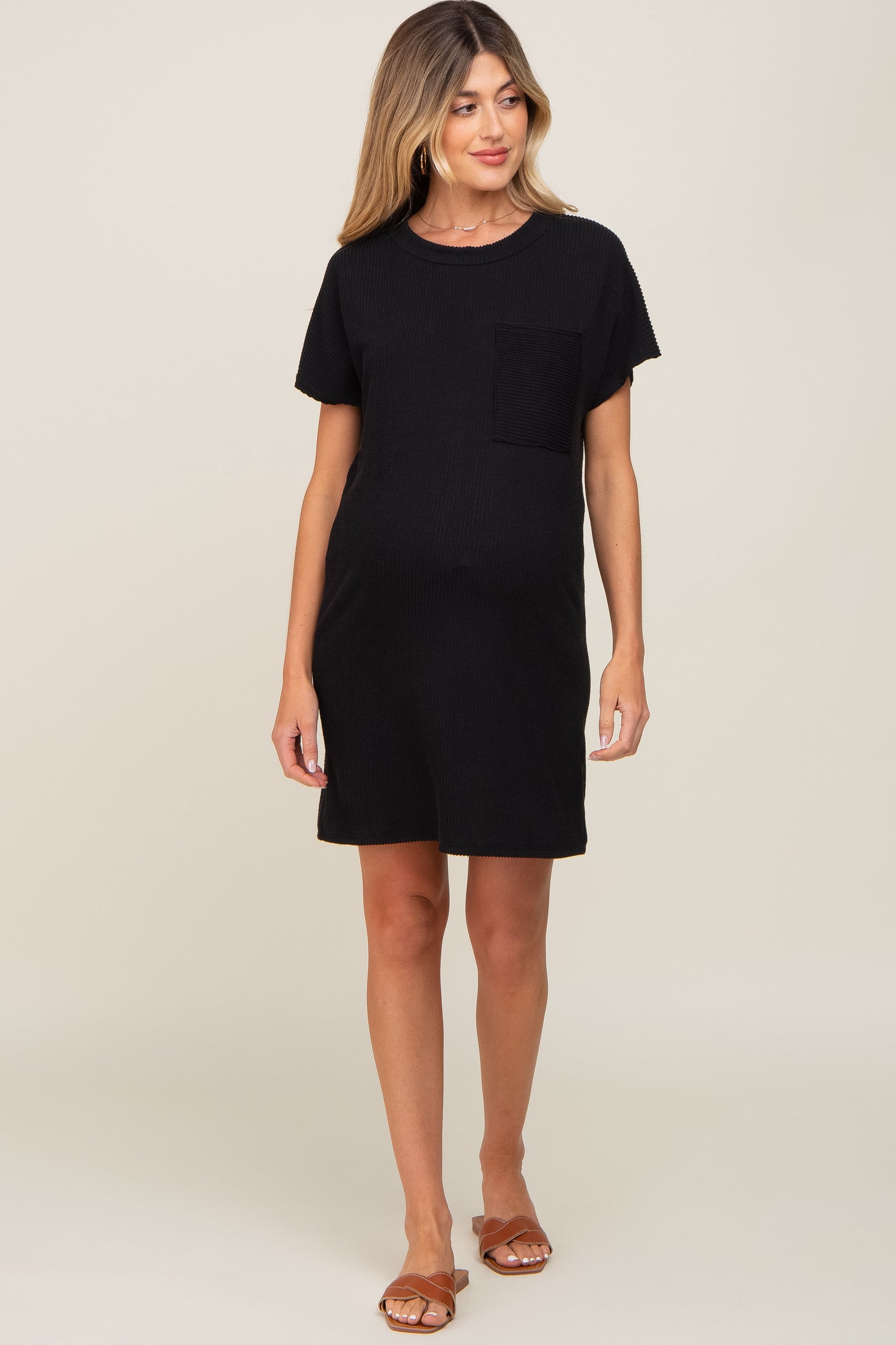 woman wearing a black short sleeve maternity dress with a chest pocket and a visible baby bump