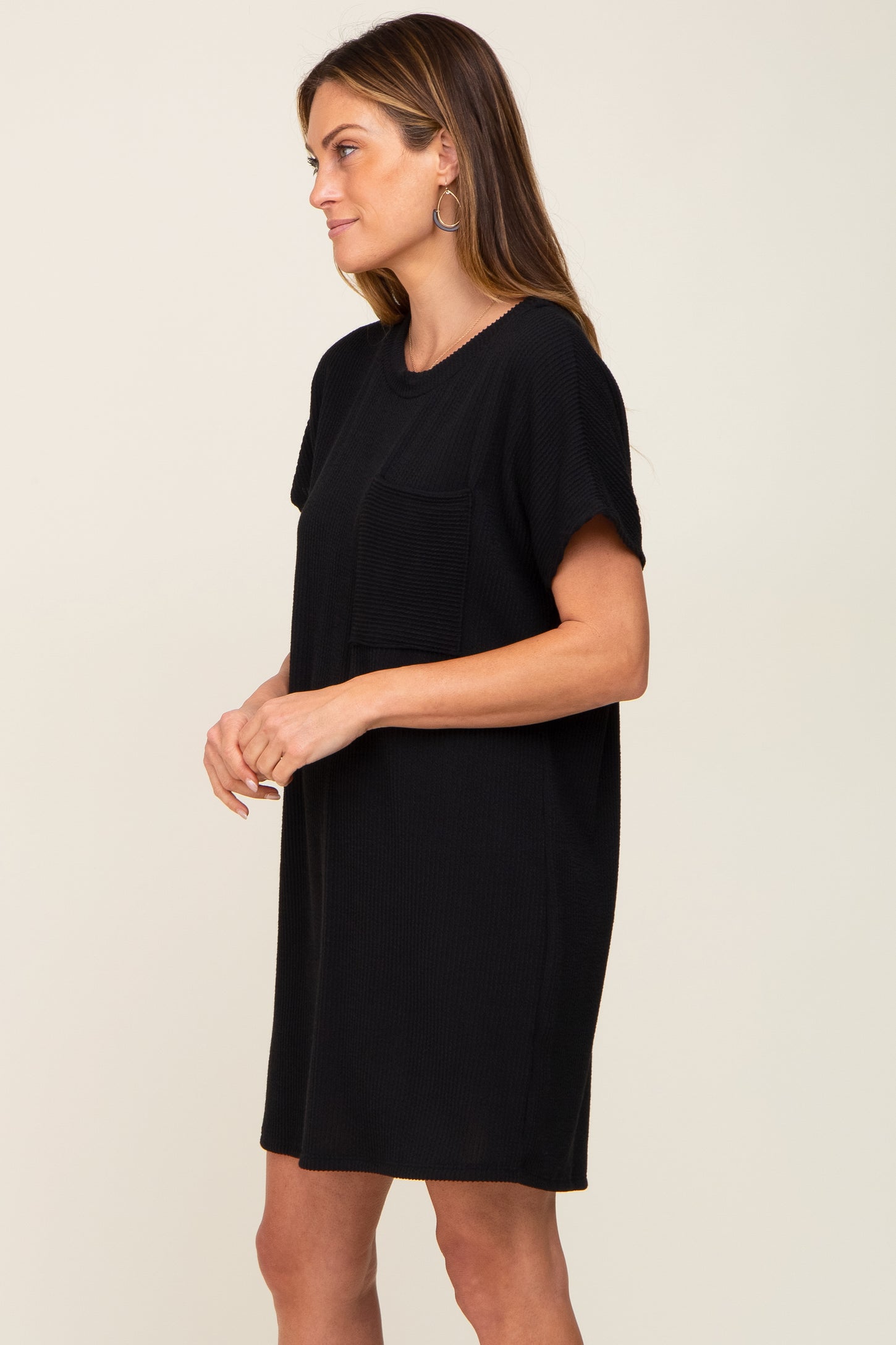 woman wearing a black short sleeve oversized pocket dress standing sideways