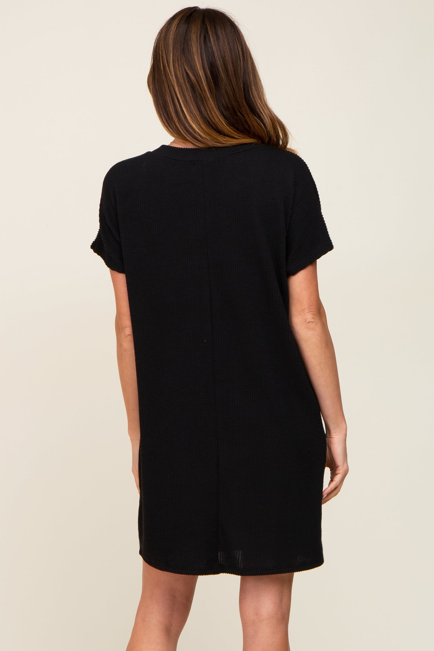 woman wearing a short sleeve black casual dress, view from the back