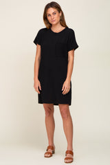 woman wearing a black short sleeve pocket dress paired with brown slide sandals