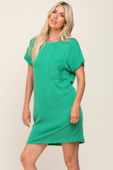 woman wearing a green ribbed short sleeve dress with a pocket on the chest