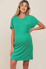 woman wearing a green ribbed short sleeve maternity dress with a front pocket and showing her baby bump