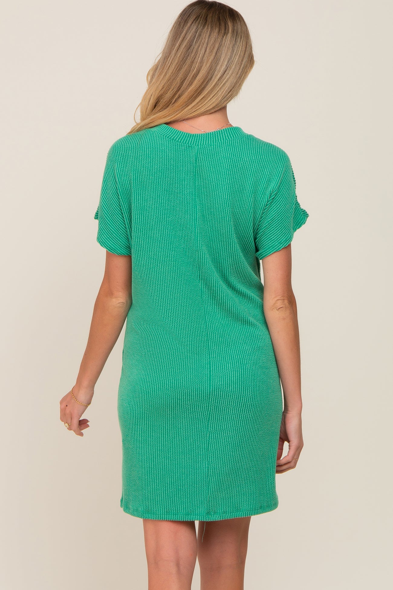 woman wearing a green striped maternity dress with short sleeves and a relaxed fit, showing her baby bump from the back