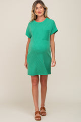 woman wearing a green ribbed maternity dress with short sleeves and a pocket, showing her baby bump